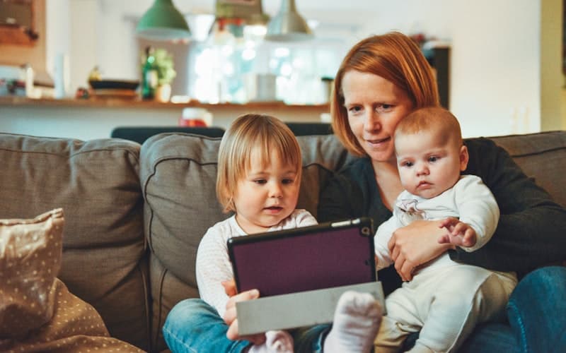 Une mère lit avec ses deux enfants sur le canapé